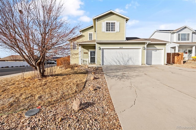 traditional-style house featuring driveway, an attached garage, and fence