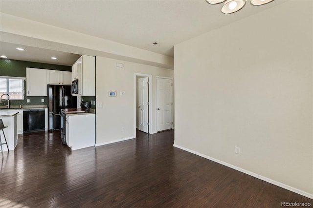 kitchen with dark wood-type flooring, white cabinetry, a sink, and black appliances