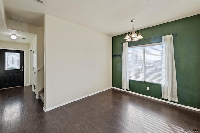 spare room with dark wood-style floors, baseboards, and an inviting chandelier