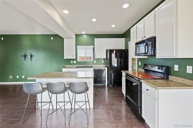 kitchen with a kitchen island, a sink, white cabinetry, light countertops, and black appliances