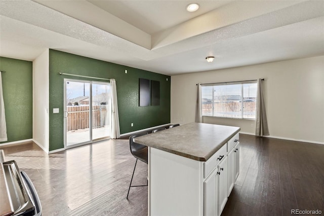 kitchen featuring baseboards, white cabinetry, dark wood-type flooring, and a center island