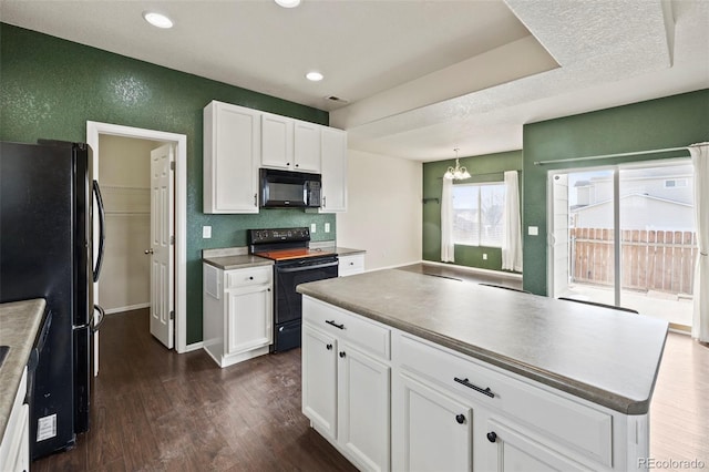 kitchen with a notable chandelier, a textured wall, dark wood-type flooring, white cabinetry, and black appliances