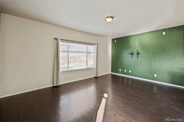 unfurnished room featuring dark wood-type flooring and baseboards