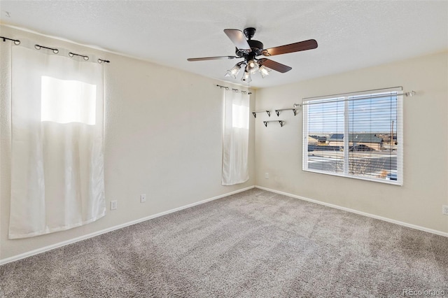 carpeted empty room with ceiling fan, baseboards, and a textured ceiling