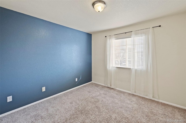 carpeted empty room with baseboards, a textured ceiling, and a textured wall