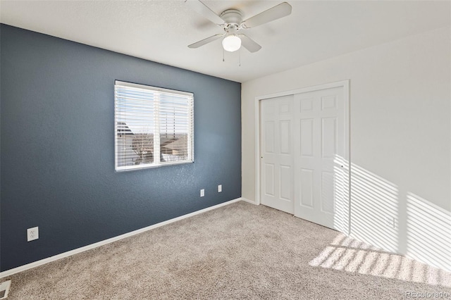 unfurnished bedroom with visible vents, baseboards, a ceiling fan, light colored carpet, and a closet