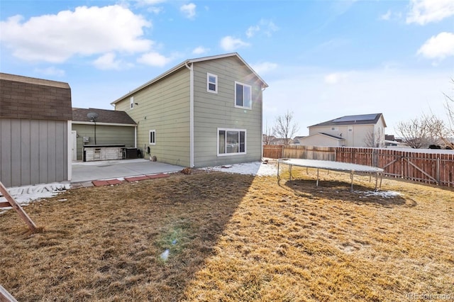 rear view of house with a trampoline, a patio area, and a fenced backyard