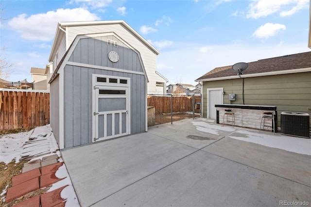 exterior space with central air condition unit, a storage unit, and fence