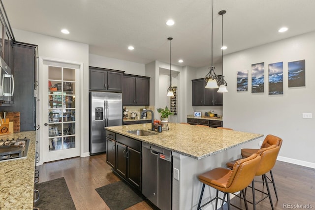 21376 E Union Pl, Aurora, CO 80015 - kitchen featuring stainless steel appliances, a sink, dark wood-style floors, light stone countertops, and a kitchen island with sink
