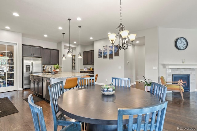 21376 E Union Pl, Aurora, CO 80015 - dining area featuring recessed lighting, dark wood finished floors, a chandelier, baseboards, and a tiled fireplace