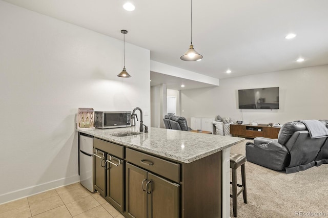 21376 E Union Pl, Aurora, CO 80015 - kitchen with open floor plan, a sink, baseboards, a kitchen bar, and light stone countertops