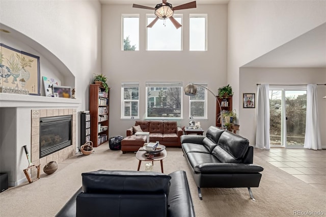 living room with tile patterned floors, a tile fireplace, ceiling fan, and a high ceiling