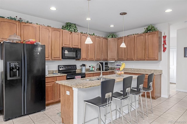 kitchen with sink, pendant lighting, a center island with sink, light tile patterned floors, and black appliances