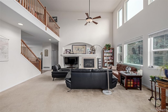 carpeted living room featuring ceiling fan and a towering ceiling