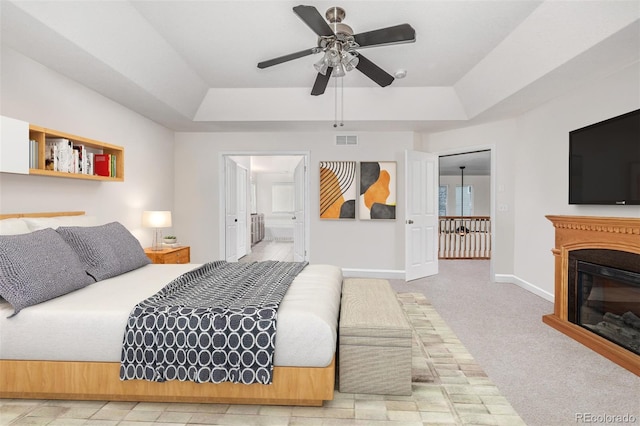 bedroom with carpet flooring, ensuite bathroom, ceiling fan, and a raised ceiling