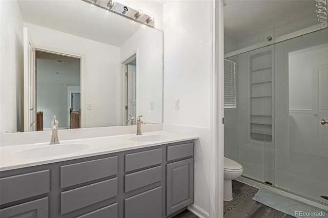 bathroom with hardwood / wood-style flooring, vanity, toilet, and walk in shower