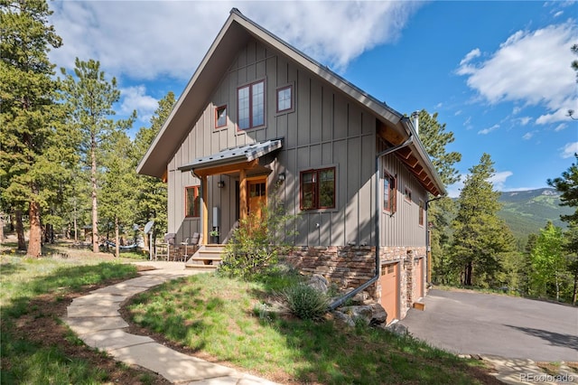 715 Clark Rd, Bailey, CO 80421 - view of front facade featuring a garage, asphalt driveway, board and batten siding, and stone siding