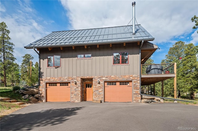 715 Clark Rd, Bailey, CO 80421 - view of front of home with an attached garage, stone siding, asphalt driveway, a standing seam roof, and a metal roof