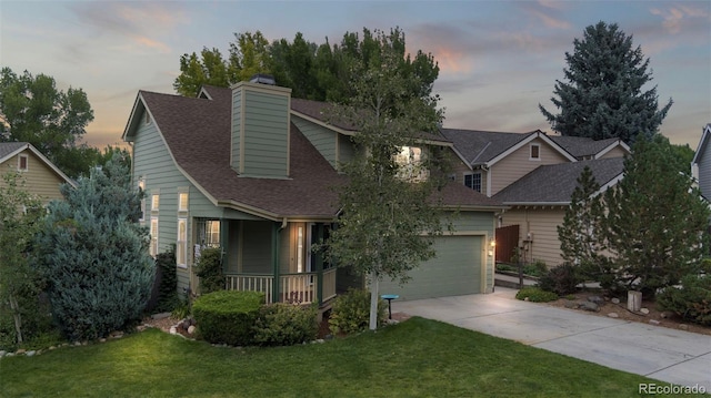 view of front of property featuring a garage, a lawn, and covered porch