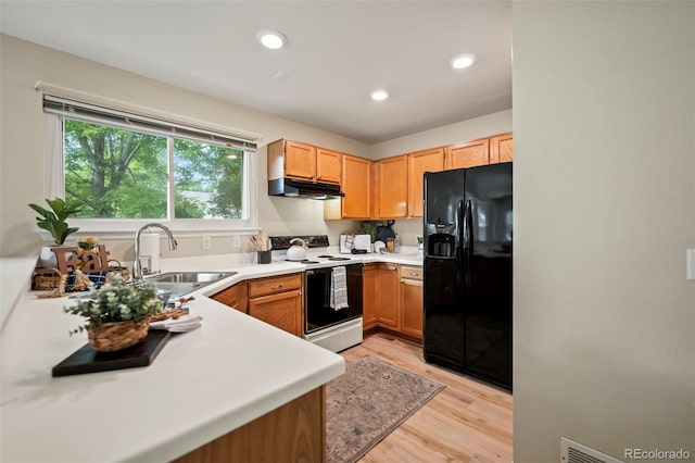 kitchen featuring sink, white electric range, light hardwood / wood-style flooring, and black fridge