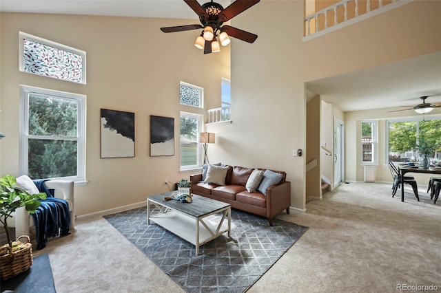 living room featuring ceiling fan, a towering ceiling, and dark carpet