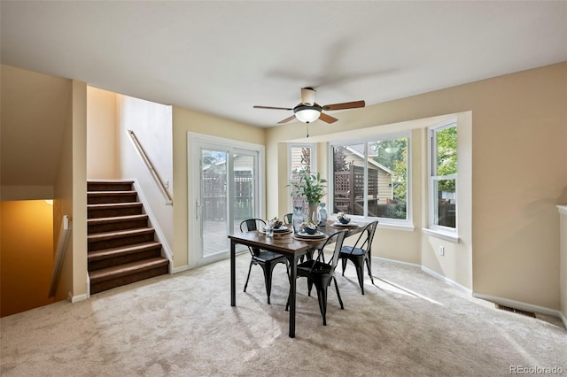 dining area with ceiling fan and light colored carpet