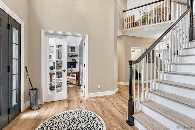 foyer with light hardwood / wood-style floors, french doors, and a high ceiling