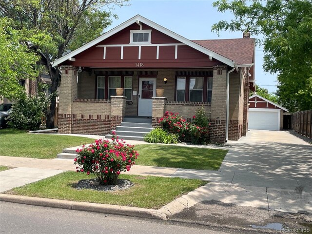 view of front of home featuring a porch, brick siding, a chimney, a detached garage, and an outdoor structure