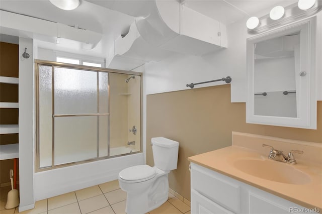 bathroom featuring toilet, vanity, tile patterned floors, bath / shower combo with glass door, and baseboards