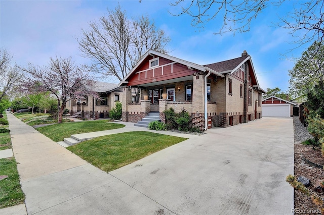 view of front of house with covered porch, a chimney, brick siding, a front yard, and an outdoor structure