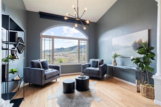 415 Butte Pkwy, Golden, CO 80403 - living area with wood finished floors, a chandelier, a mountain view, vaulted ceiling, and baseboards