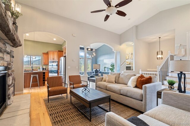 415 Butte Pkwy, Golden, CO 80403 - living area featuring arched walkways, ceiling fan, light wood-type flooring, a chandelier, and high vaulted ceiling