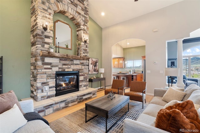 415 Butte Pkwy, Golden, CO 80403 - living room featuring wood finished floors, a stone fireplace, high vaulted ceiling, arched walkways, and ornate columns