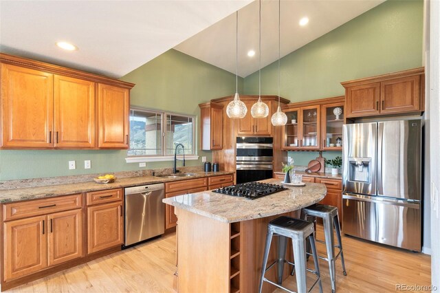 415 Butte Pkwy, Golden, CO 80403 - kitchen with appliances with stainless steel finishes, a sink, brown cabinetry, high vaulted ceiling, and a kitchen island