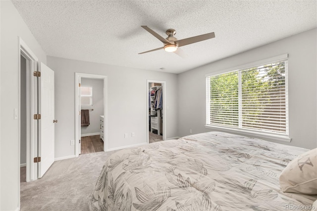 10591 Hyacinth St, Highlands Ranch, CO 80129 - carpeted bedroom featuring a walk in closet, a textured ceiling, a closet, ensuite bath, and a ceiling fan