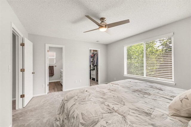 10591 Hyacinth St, Highlands Ranch, CO 80129 - carpeted bedroom with a walk in closet, a textured ceiling, a closet, ensuite bath, and ceiling fan