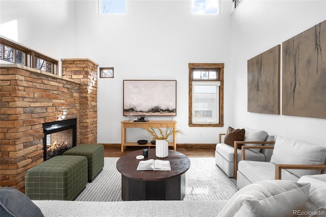 living room featuring a high ceiling, baseboards, wood finished floors, and a multi sided fireplace