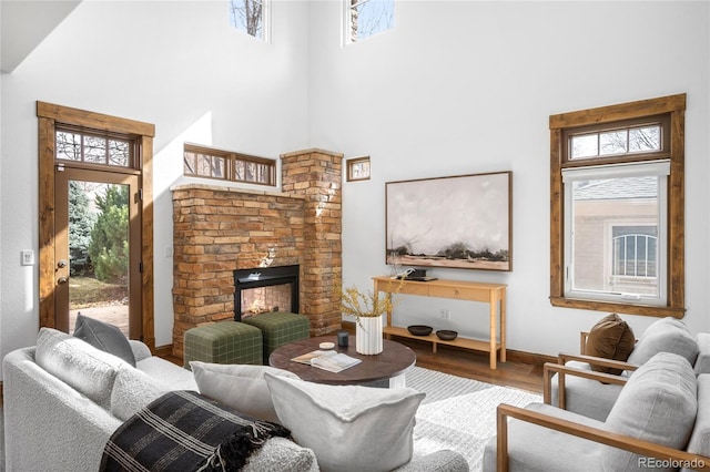 living room featuring wood finished floors, a multi sided fireplace, a towering ceiling, and baseboards