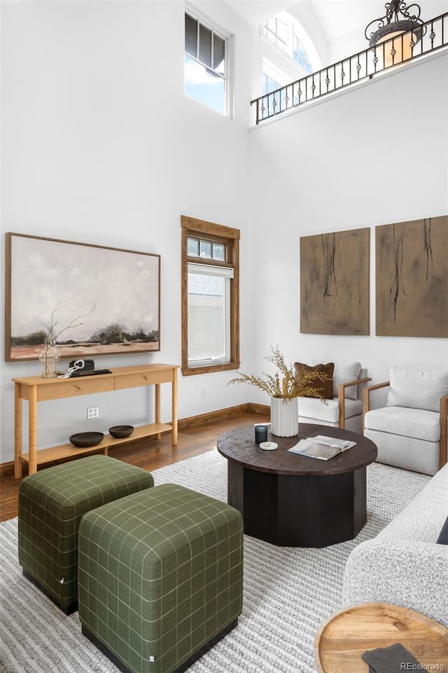 living room with a towering ceiling, baseboards, and wood finished floors