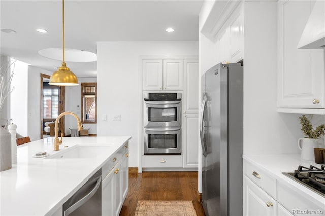 kitchen featuring appliances with stainless steel finishes, dark wood-style flooring, custom exhaust hood, white cabinetry, and a sink