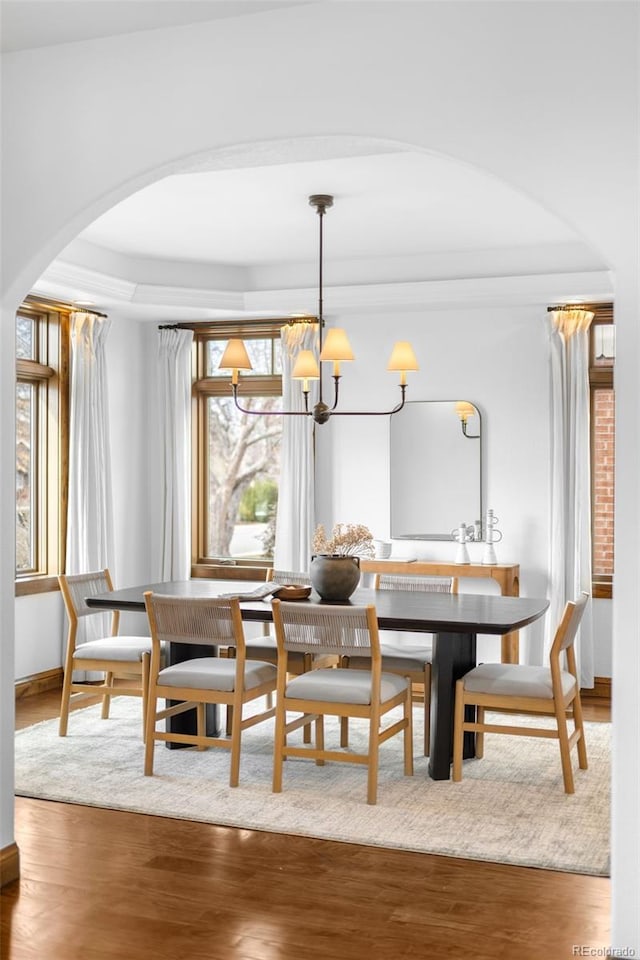 dining area with a chandelier, arched walkways, and wood finished floors