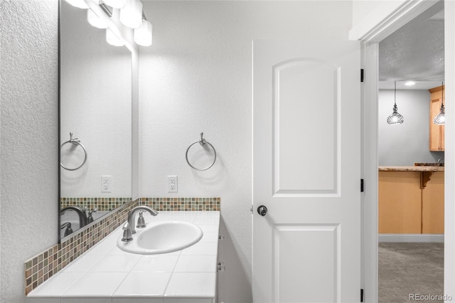 bathroom featuring a textured wall and vanity