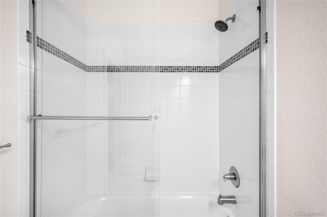 full bath with a textured wall and combined bath / shower with glass door