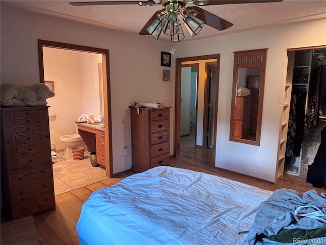 3910 E Orchard Rd, Centennial, CO 80121 - bedroom featuring a walk in closet, ensuite bathroom, a closet, light wood-type flooring, and a ceiling fan