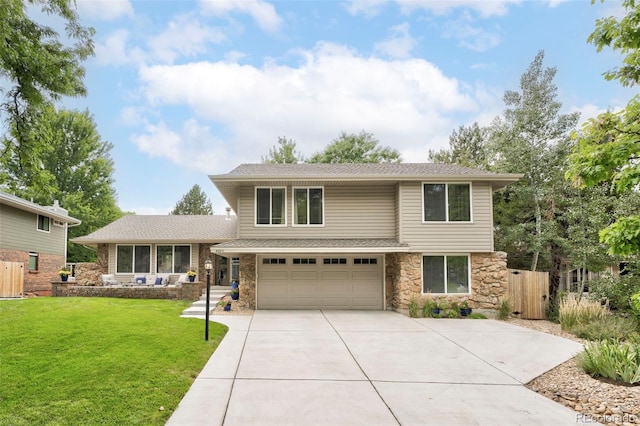 view of front facade featuring a front lawn, fence, concrete driveway, a garage, and stone siding