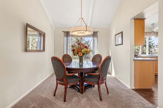 carpeted dining space featuring a sink, baseboards, and vaulted ceiling