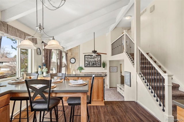 dining area featuring visible vents, vaulted ceiling with beams, stairs, dark wood-style floors, and a ceiling fan