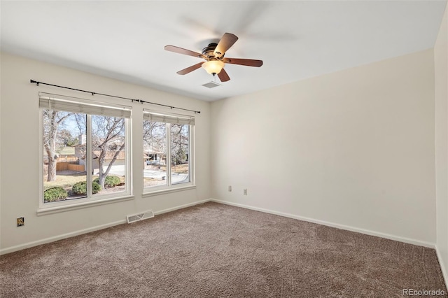 spare room with visible vents, carpet floors, baseboards, and ceiling fan