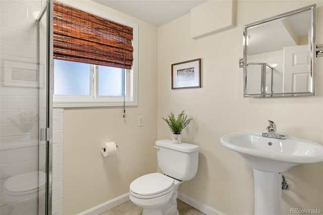 bathroom featuring a shower stall, toilet, baseboards, and a sink