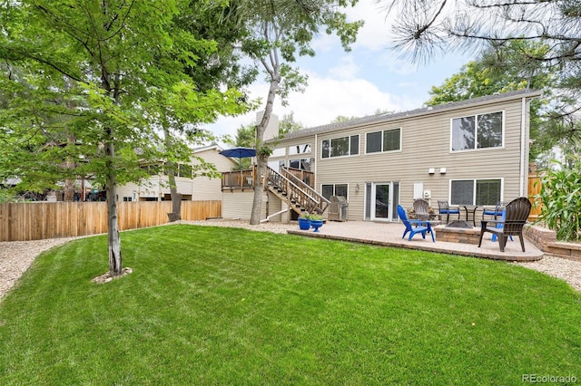 rear view of property featuring a lawn, a deck, a patio, fence, and stairs